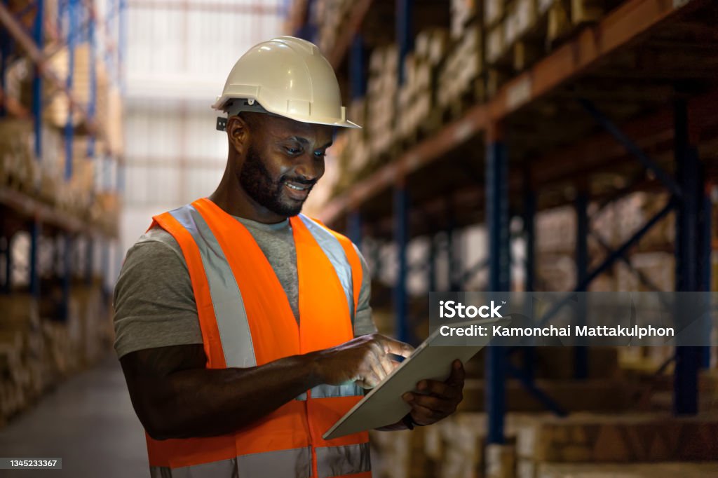 Workers holding helmets discuss GMG EnviroSafe safety compliance training in a warehouse setting