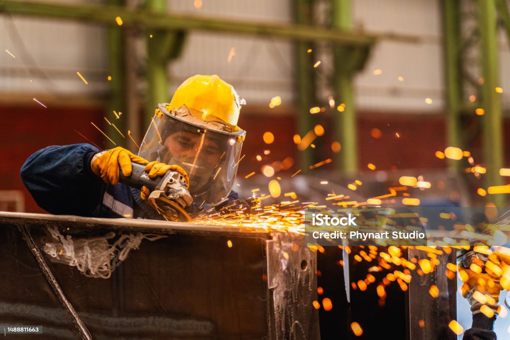 Workers holding helmets discuss GMG EnviroSafe safety compliance training in a warehouse setting