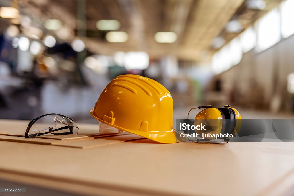 Workers holding helmets discuss GMG EnviroSafe safety compliance training in a warehouse setting