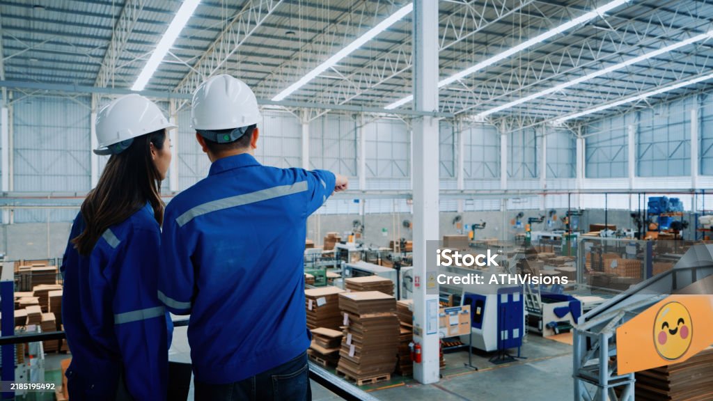 Workers holding helmets discuss GMG EnviroSafe safety compliance training in a warehouse setting