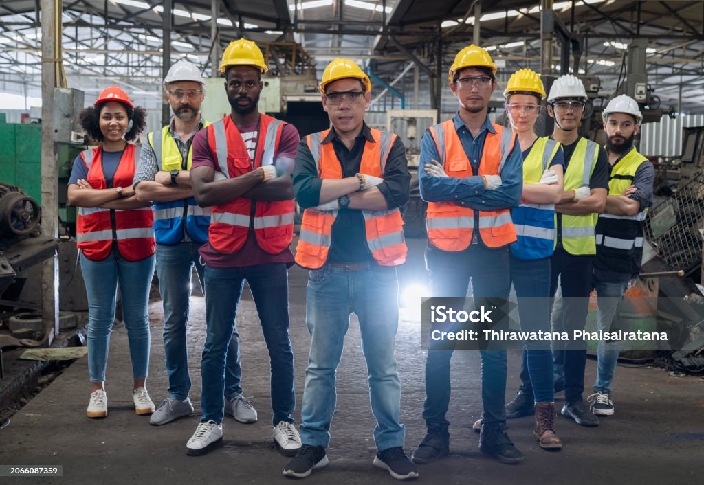 Workers holding helmets discuss GMG EnviroSafe safety compliance training in a warehouse setting