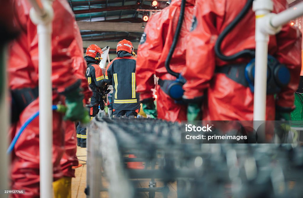 Workers holding helmets discuss GMG EnviroSafe safety compliance training in a warehouse setting