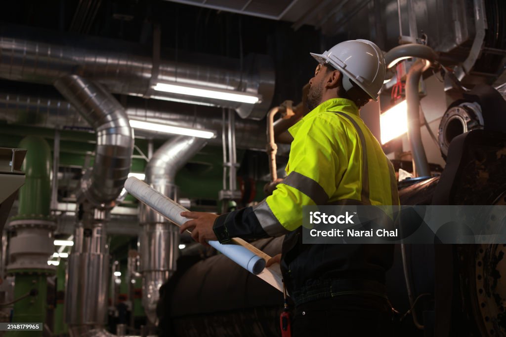 Workers holding helmets discuss GMG EnviroSafe safety compliance training in a warehouse setting
