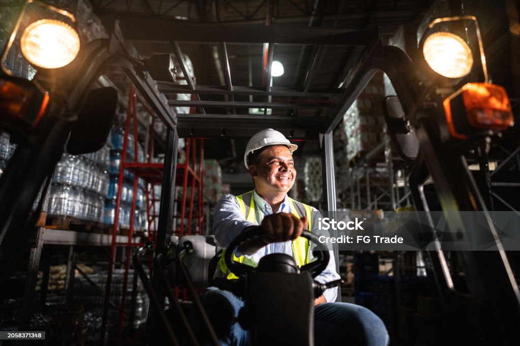 Workers holding helmets discuss GMG EnviroSafe safety compliance training in a warehouse setting