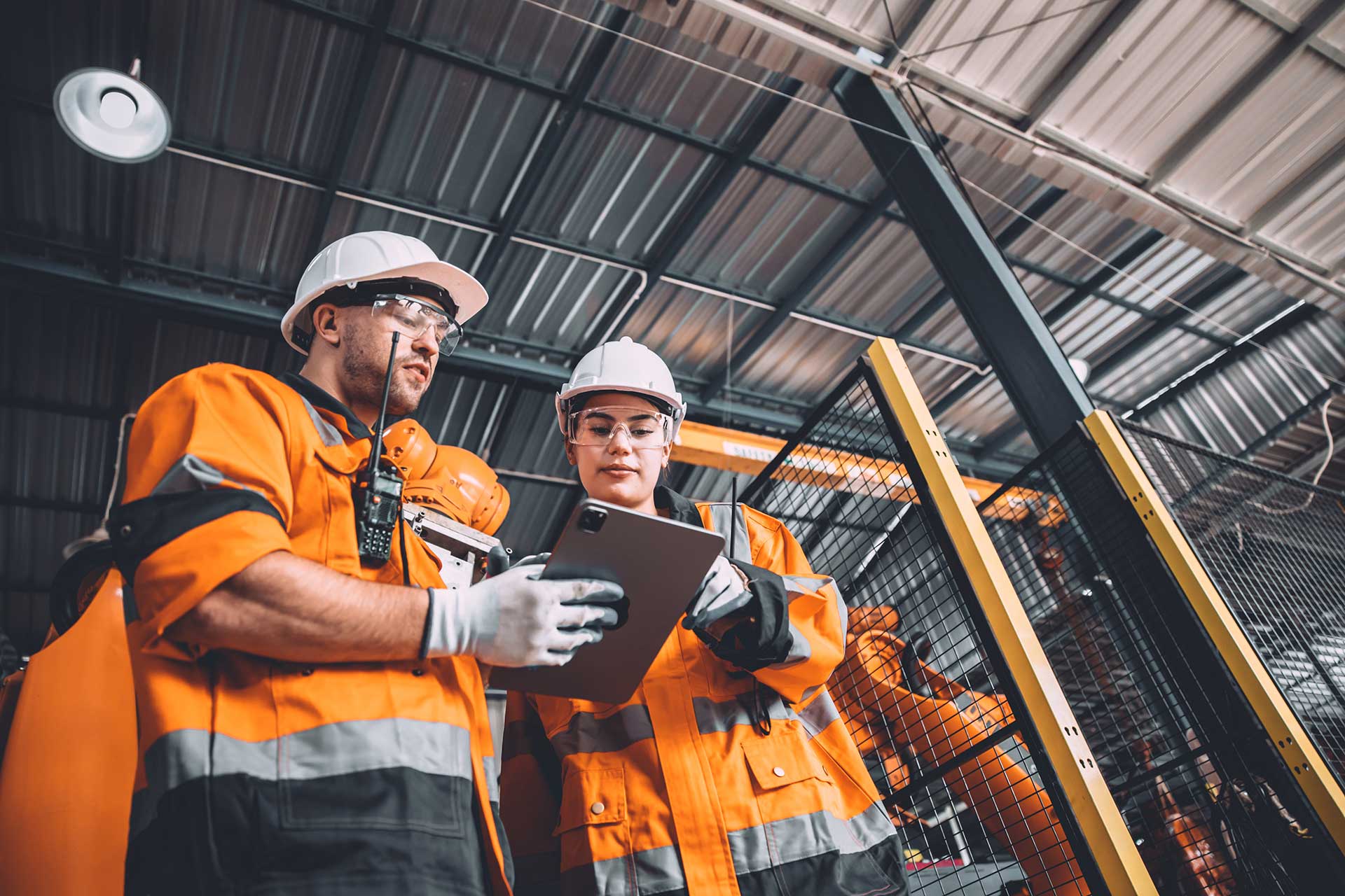Workers holding helmets discuss GMG EnviroSafe safety compliance training in a warehouse setting