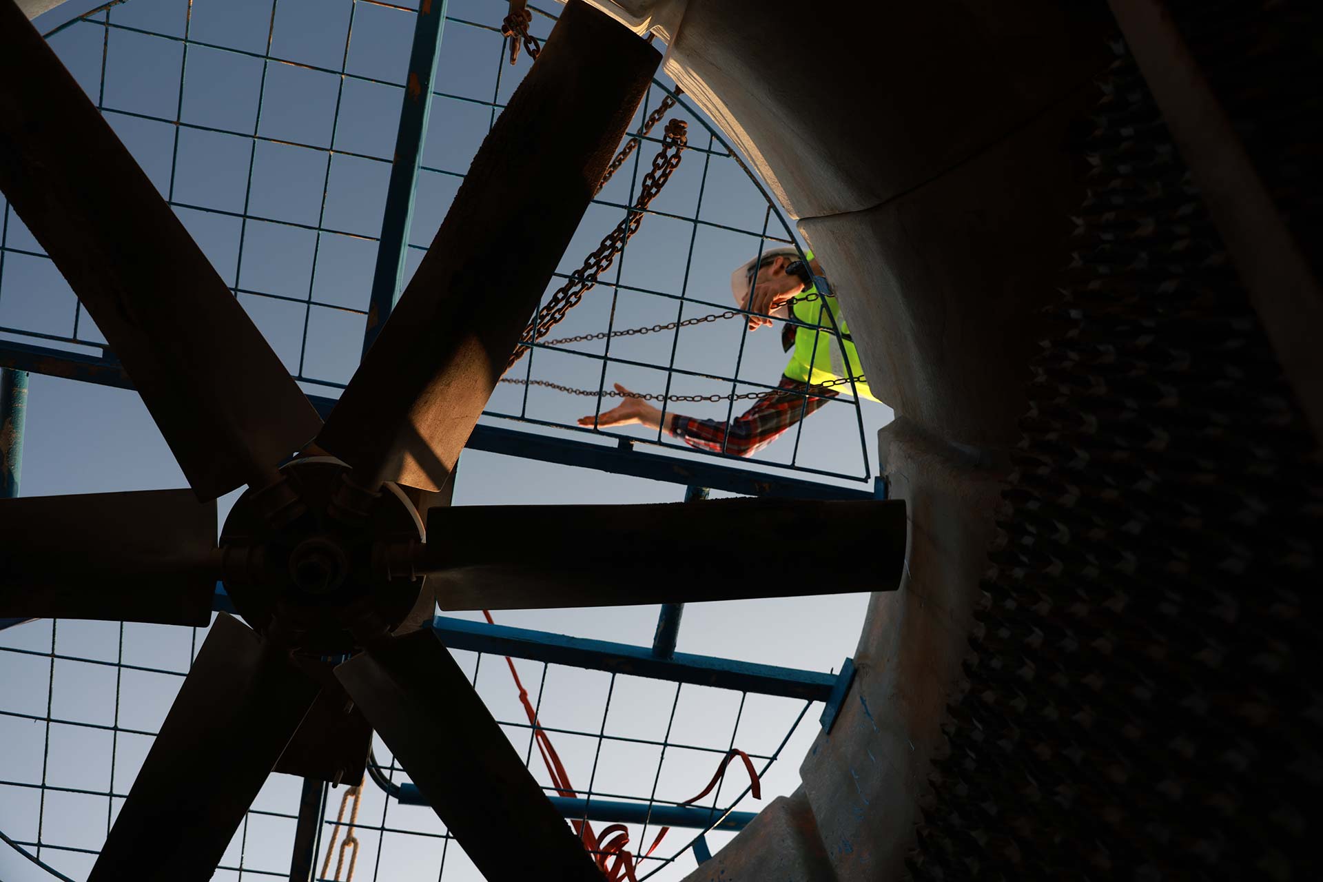 Workers holding helmets discuss GMG EnviroSafe safety compliance training in a warehouse setting