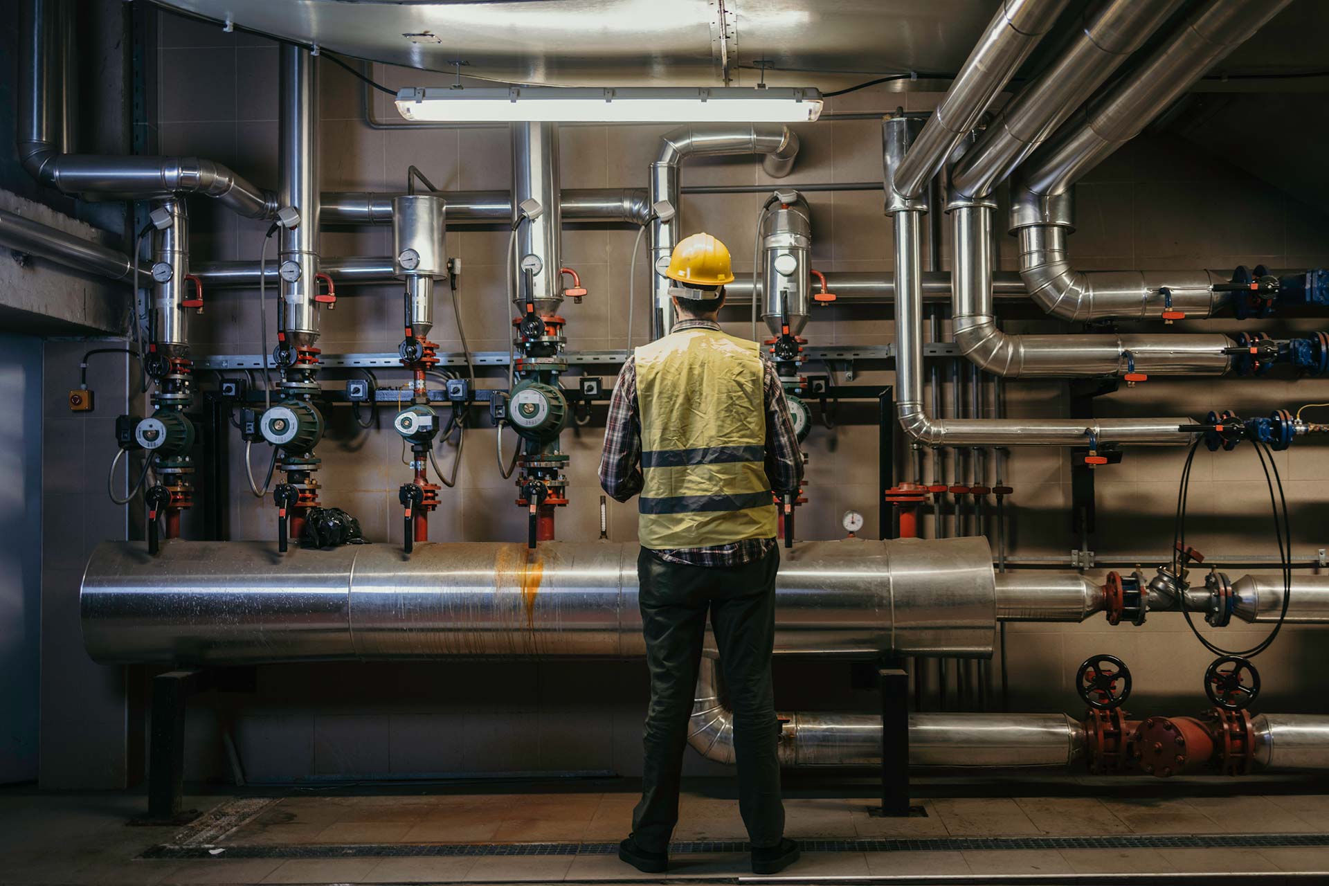 Workers holding helmets discuss GMG EnviroSafe safety compliance training in a warehouse setting