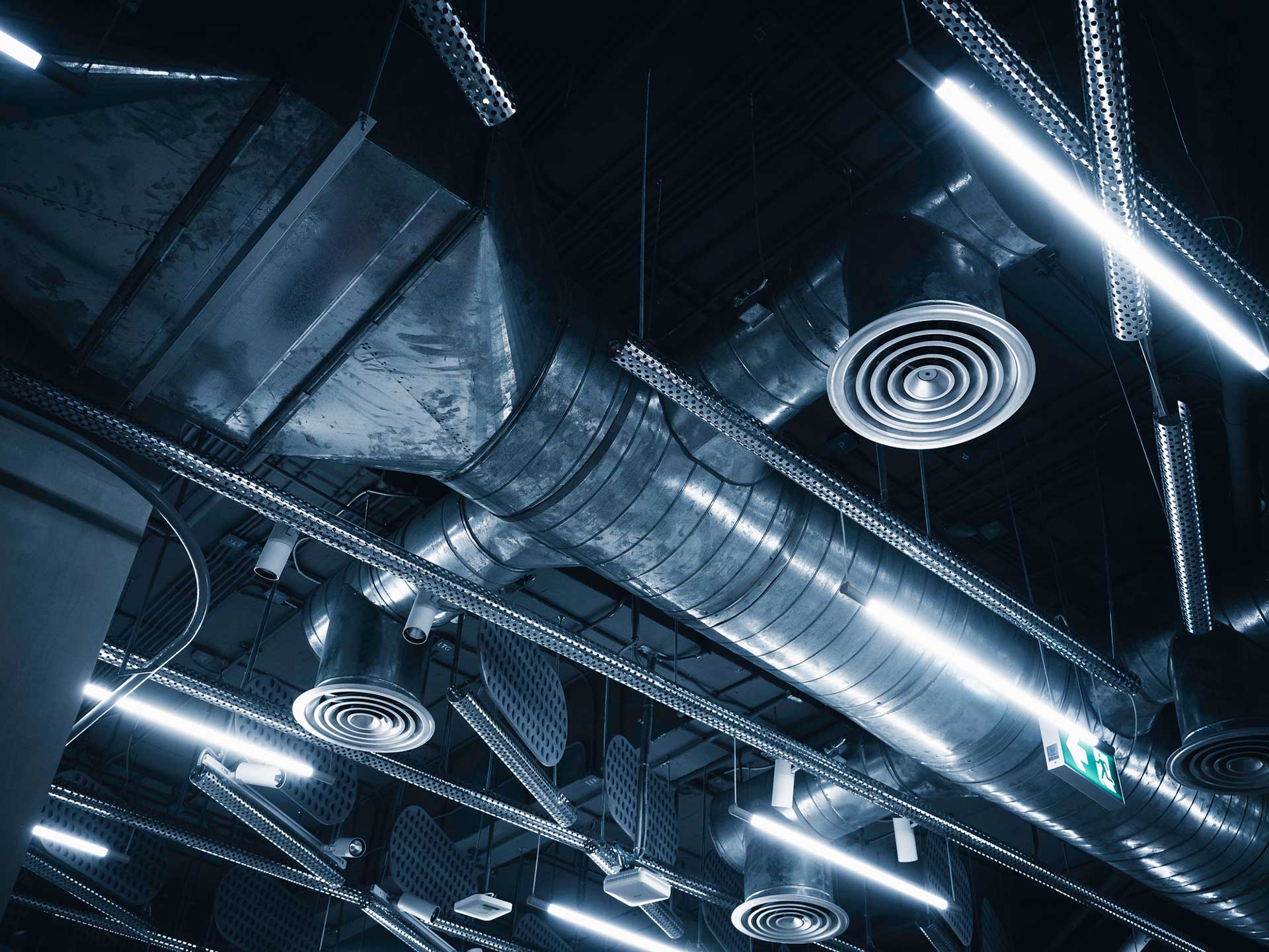 Workers holding helmets discuss GMG EnviroSafe safety compliance training in a warehouse setting