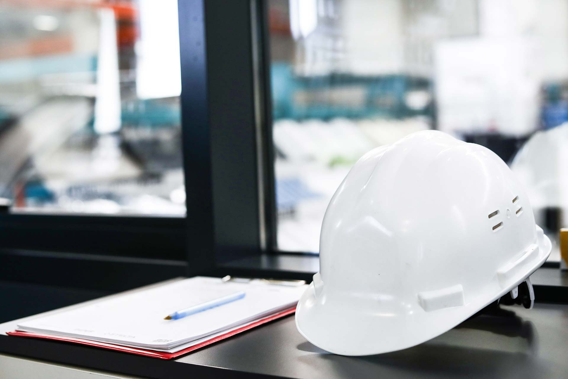 Workers holding helmets discuss GMG EnviroSafe safety compliance training in a warehouse setting