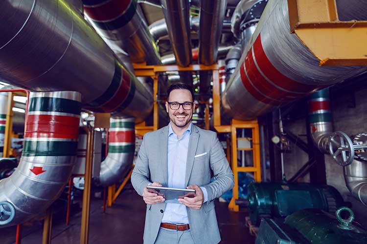 Workers holding helmets discuss GMG EnviroSafe safety compliance training in a warehouse setting
