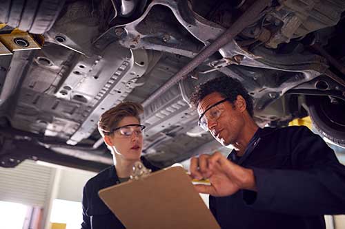 Mechanic checks car undercarriage in GMG-compliant noise-controlled workshop