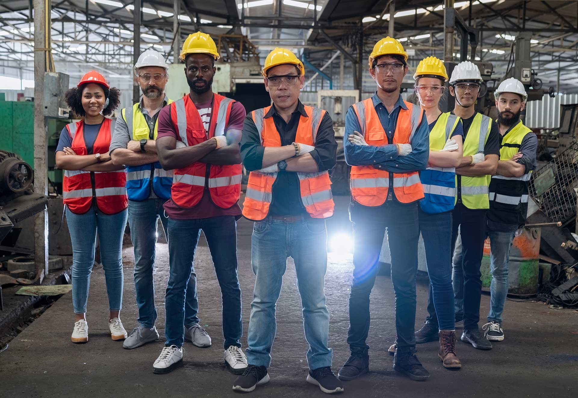 Workers holding helmets discuss GMG EnviroSafe safety compliance training in a warehouse setting