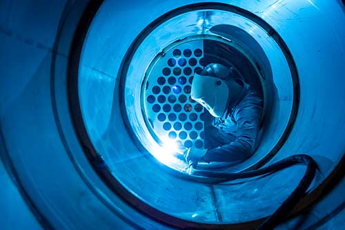 Technician in a mask smiles, breathing easy with GMG’s air quality standards
