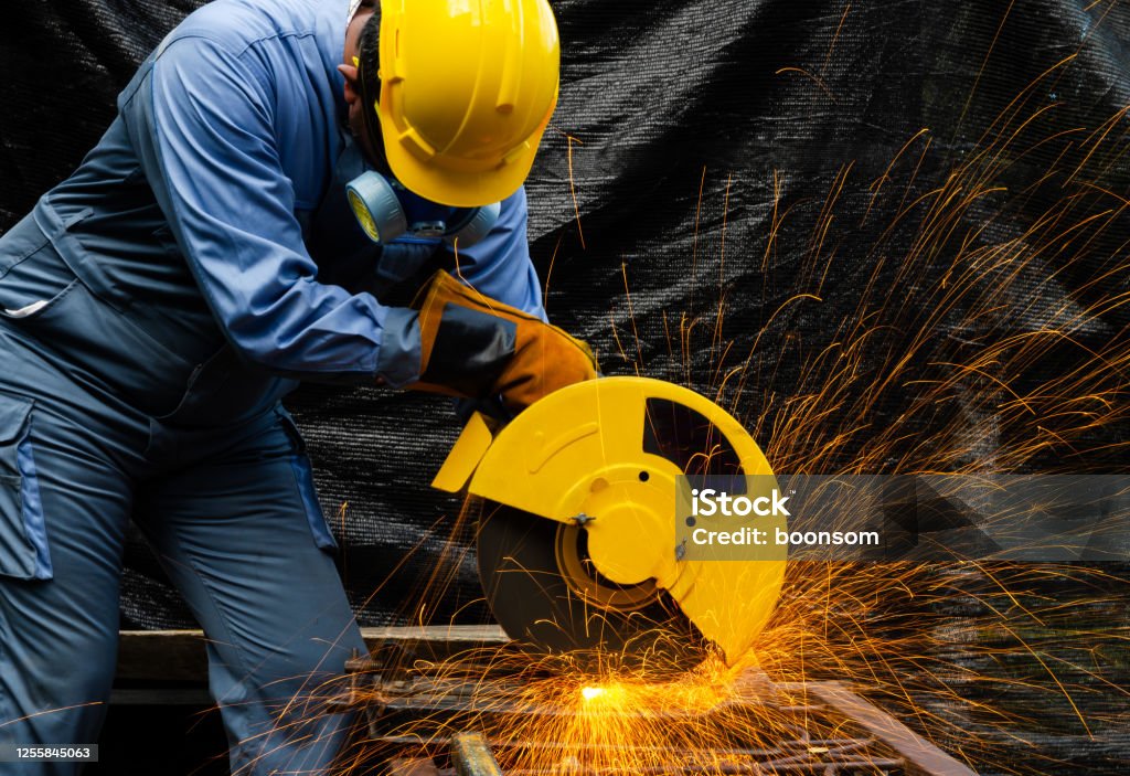 Workers holding helmets discuss GMG EnviroSafe safety compliance training in a warehouse setting