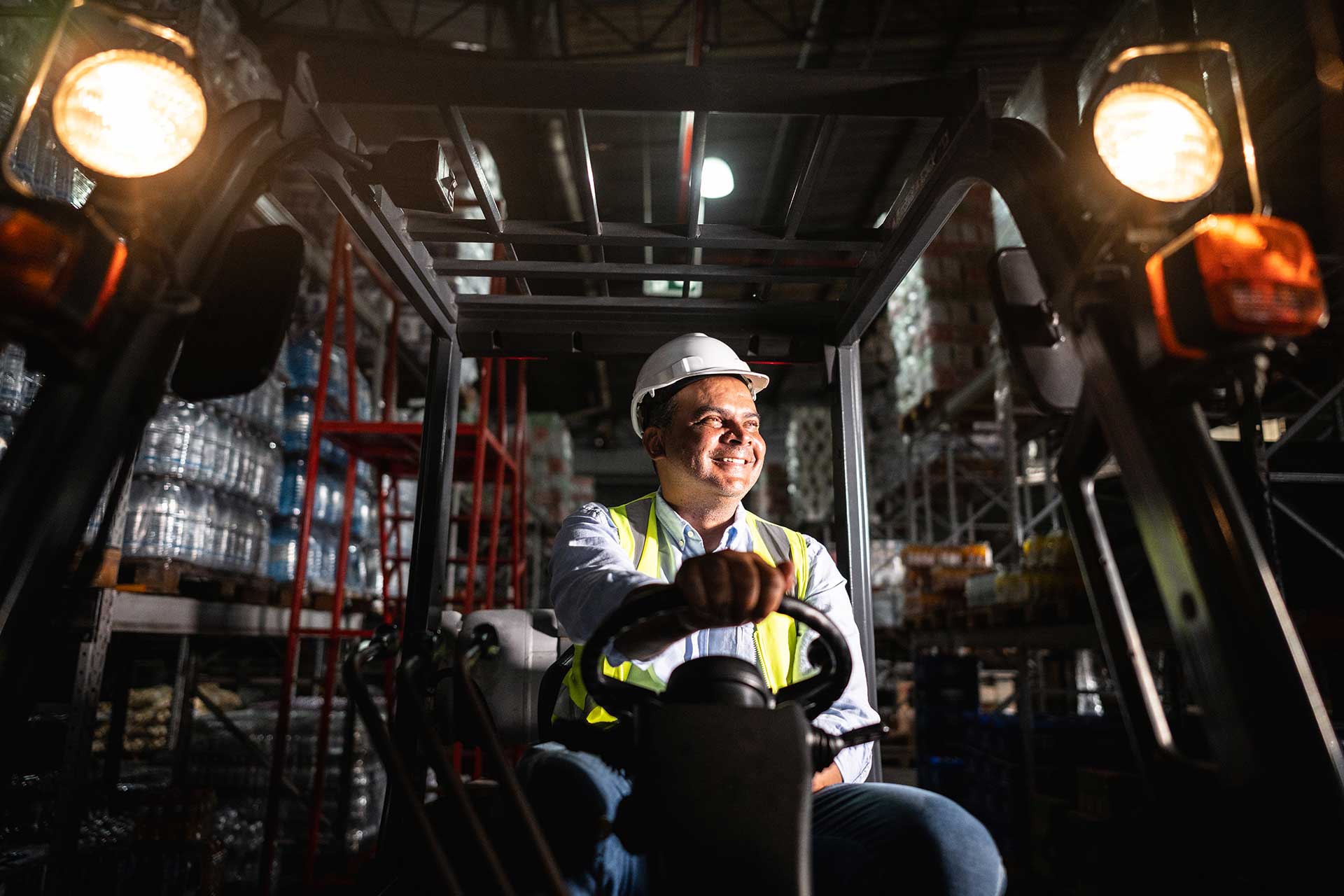 Workers holding helmets discuss GMG EnviroSafe safety compliance training in a warehouse setting