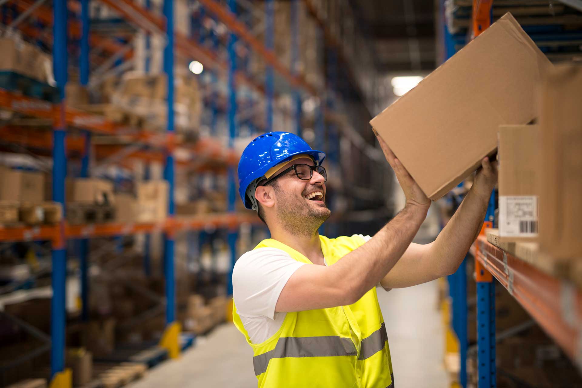 Workers holding helmets discuss GMG EnviroSafe safety compliance training in a warehouse setting