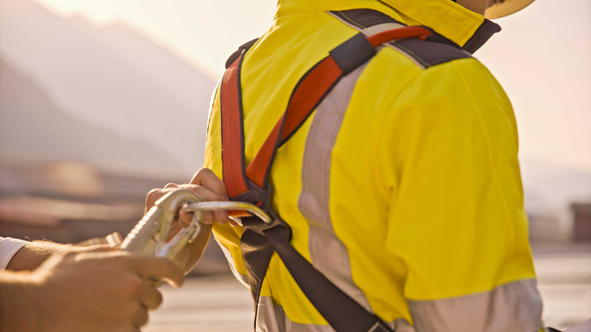 Workers holding helmets discuss GMG EnviroSafe safety compliance training in a warehouse setting