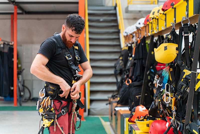 Workers holding helmets discuss GMG EnviroSafe safety compliance training in a warehouse setting