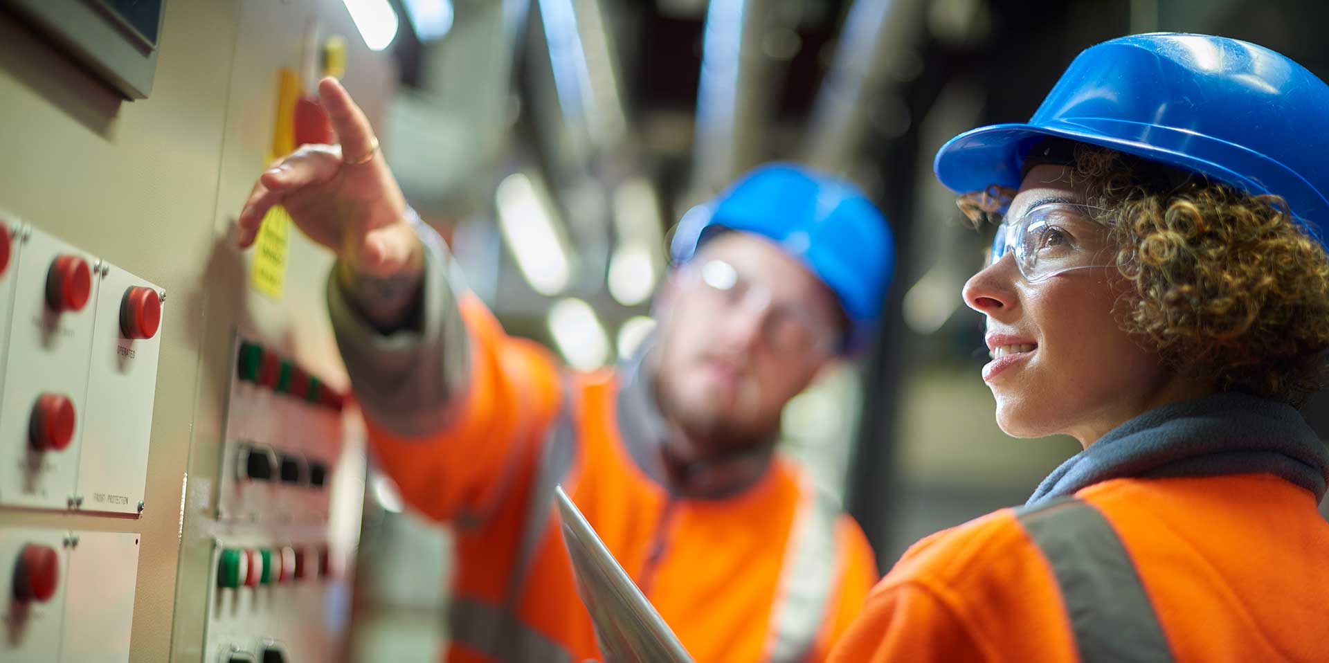 Workers holding helmets discuss GMG EnviroSafe safety compliance training in a warehouse setting