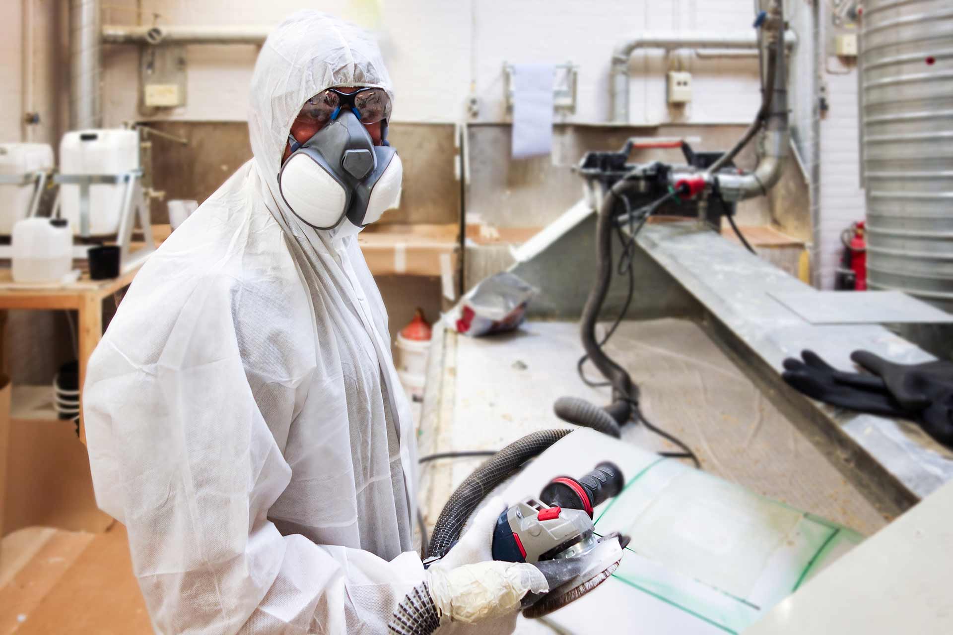 Technician spray painting car with GMG's EHS-compliant collision repair solutions