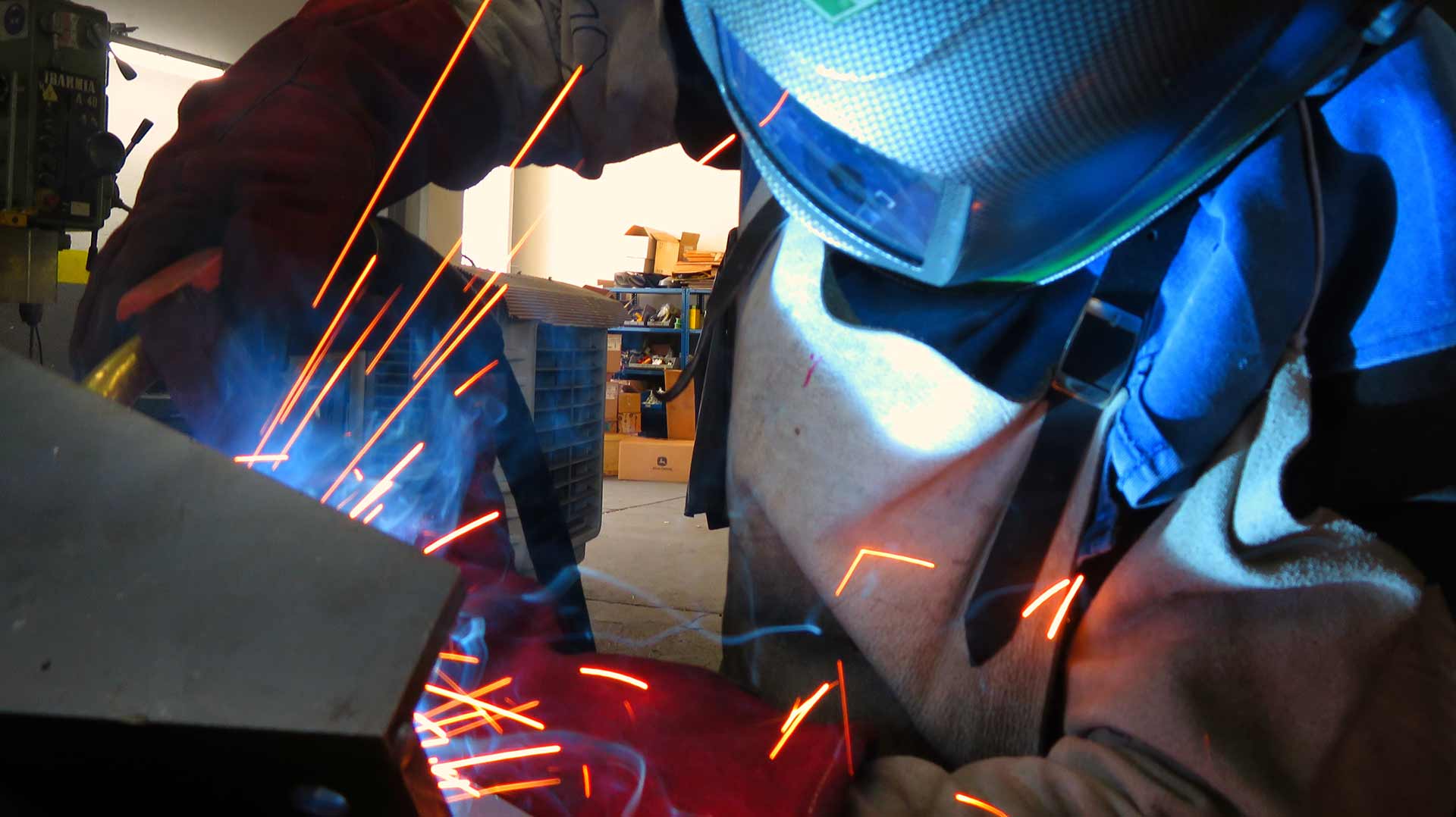 Workers holding helmets discuss GMG EnviroSafe safety compliance training in a warehouse setting