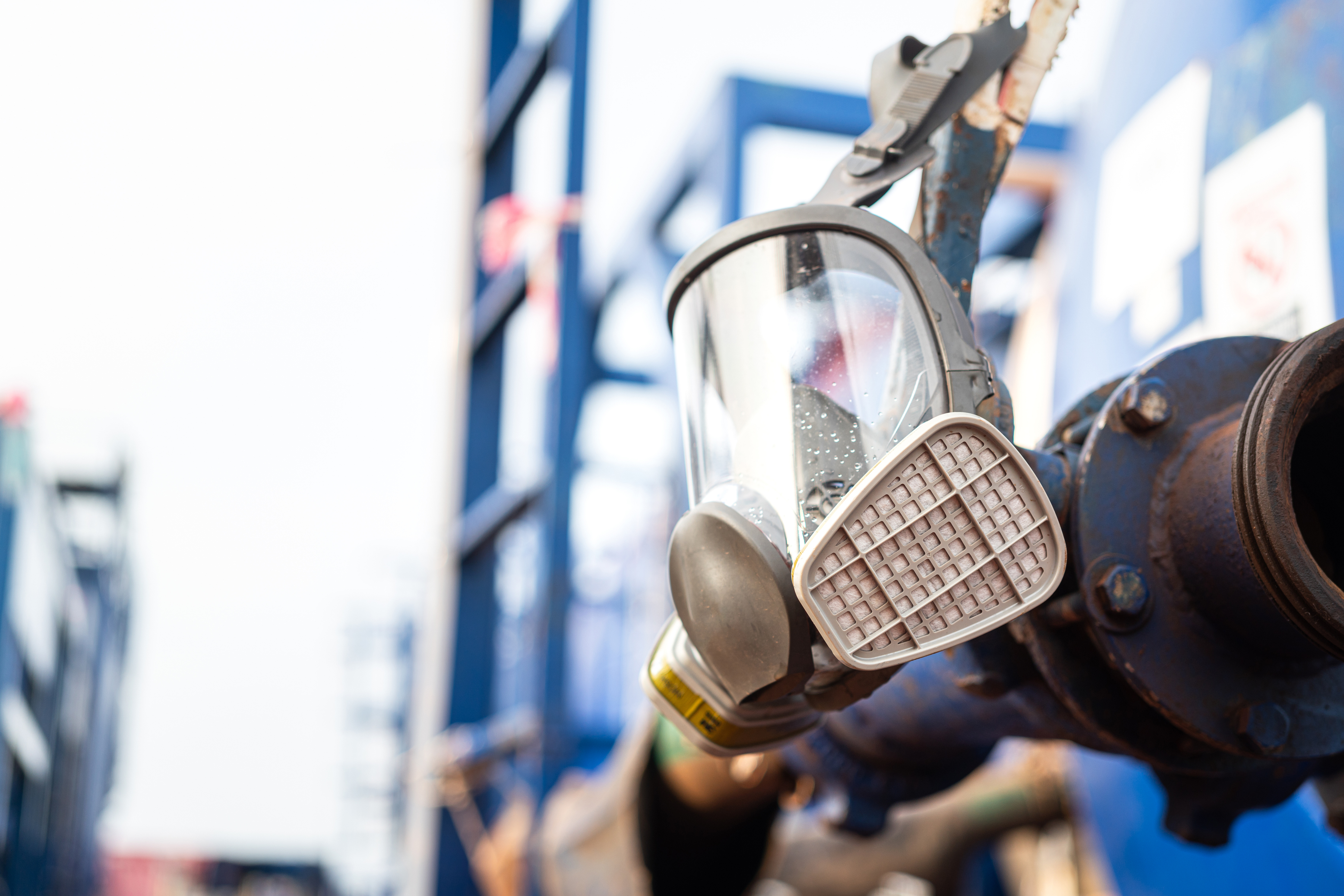 Workers holding helmets discuss GMG EnviroSafe safety compliance training in a warehouse setting