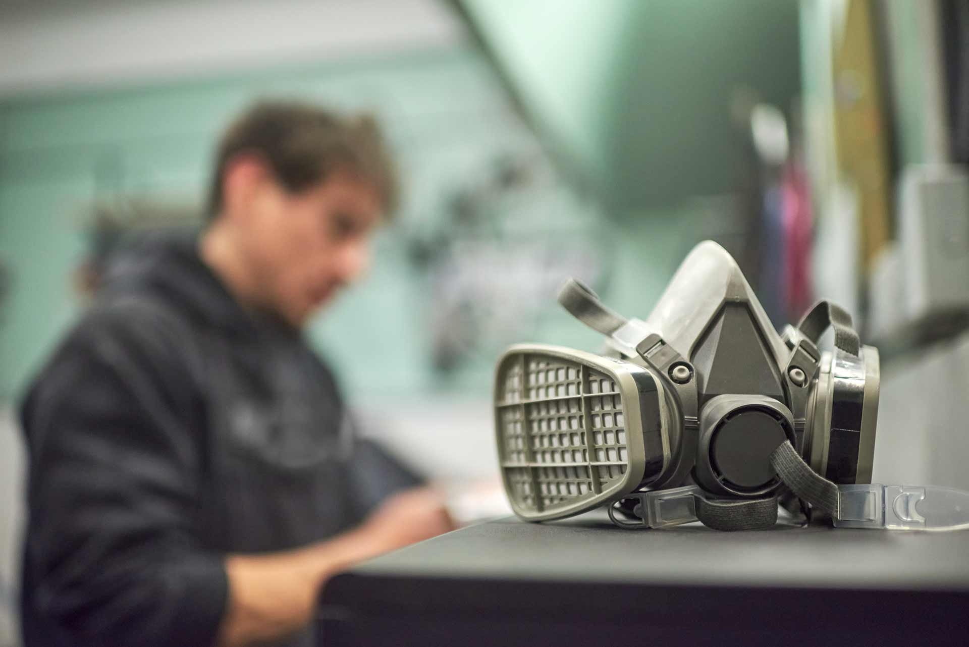 Workers holding helmets discuss GMG EnviroSafe safety compliance training in a warehouse setting