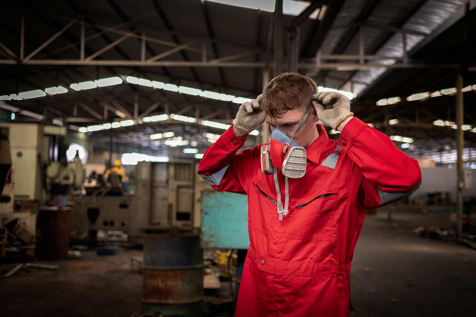 Workers holding helmets discuss GMG EnviroSafe safety compliance training in a warehouse setting