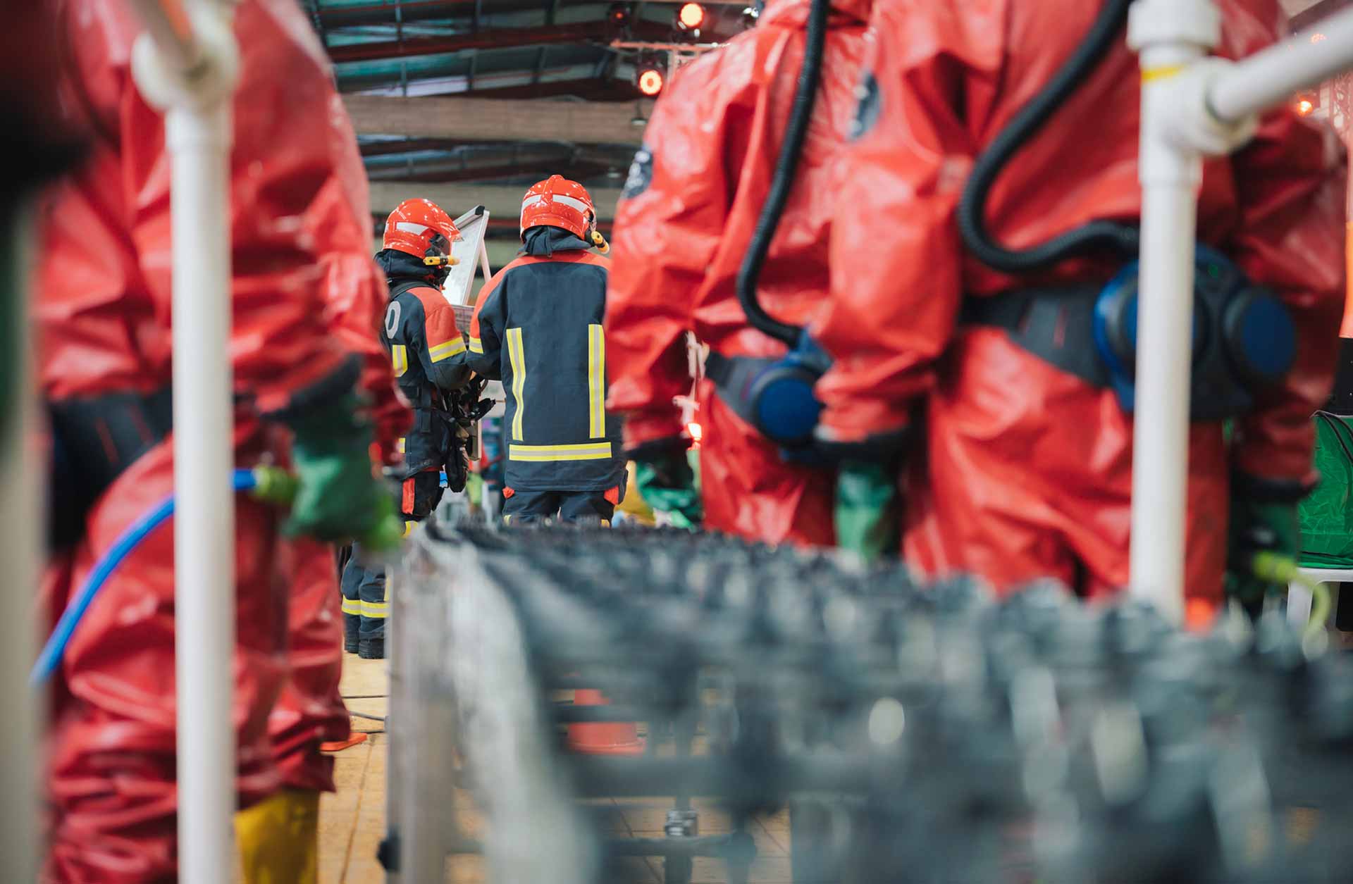 Workers holding helmets discuss GMG EnviroSafe safety compliance training in a warehouse setting