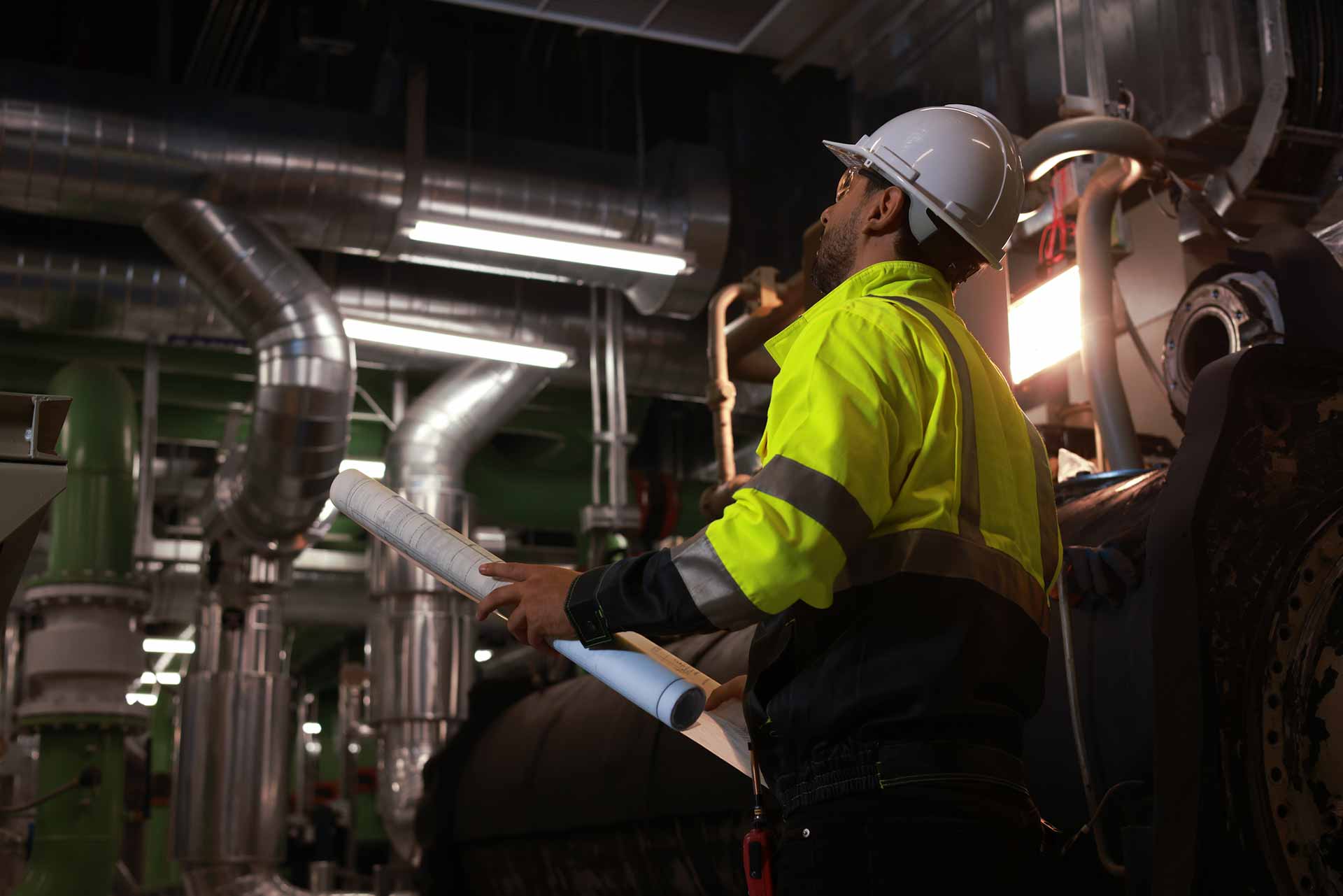Workers holding helmets discuss GMG EnviroSafe safety compliance training in a warehouse setting
