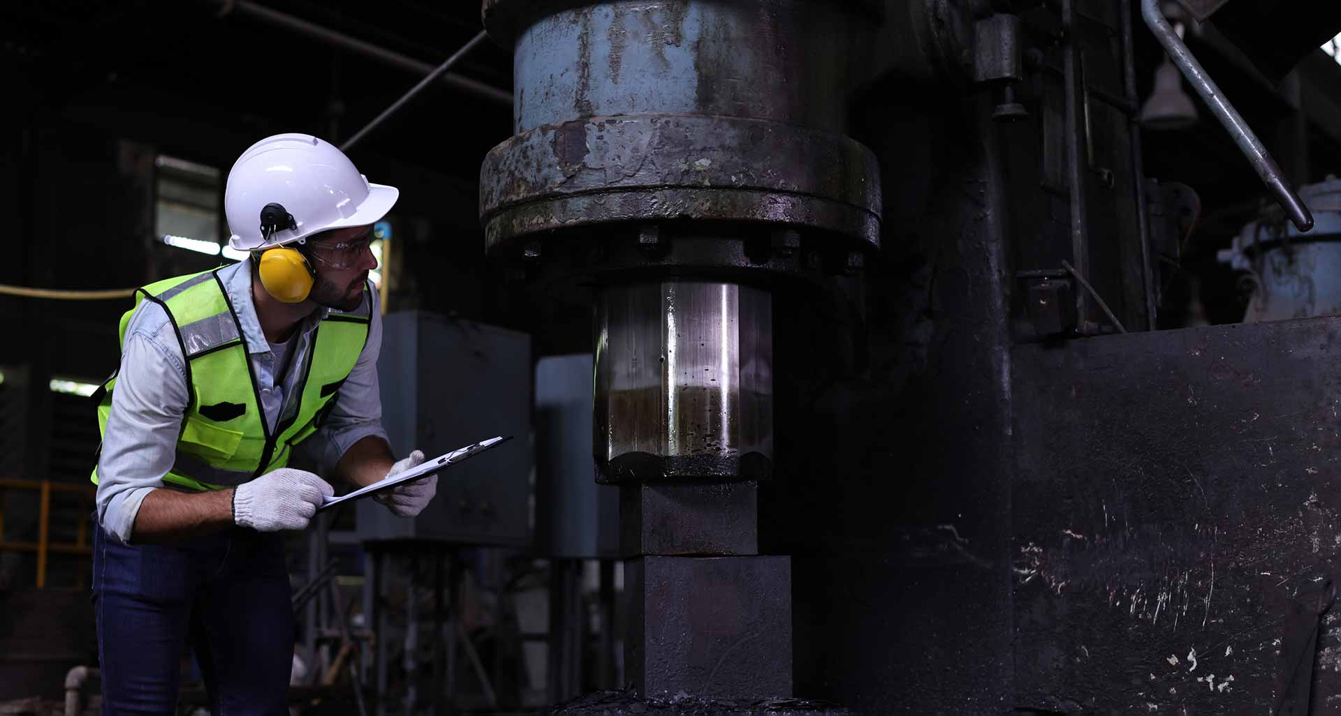Workers holding helmets discuss GMG EnviroSafe safety compliance training in a warehouse setting