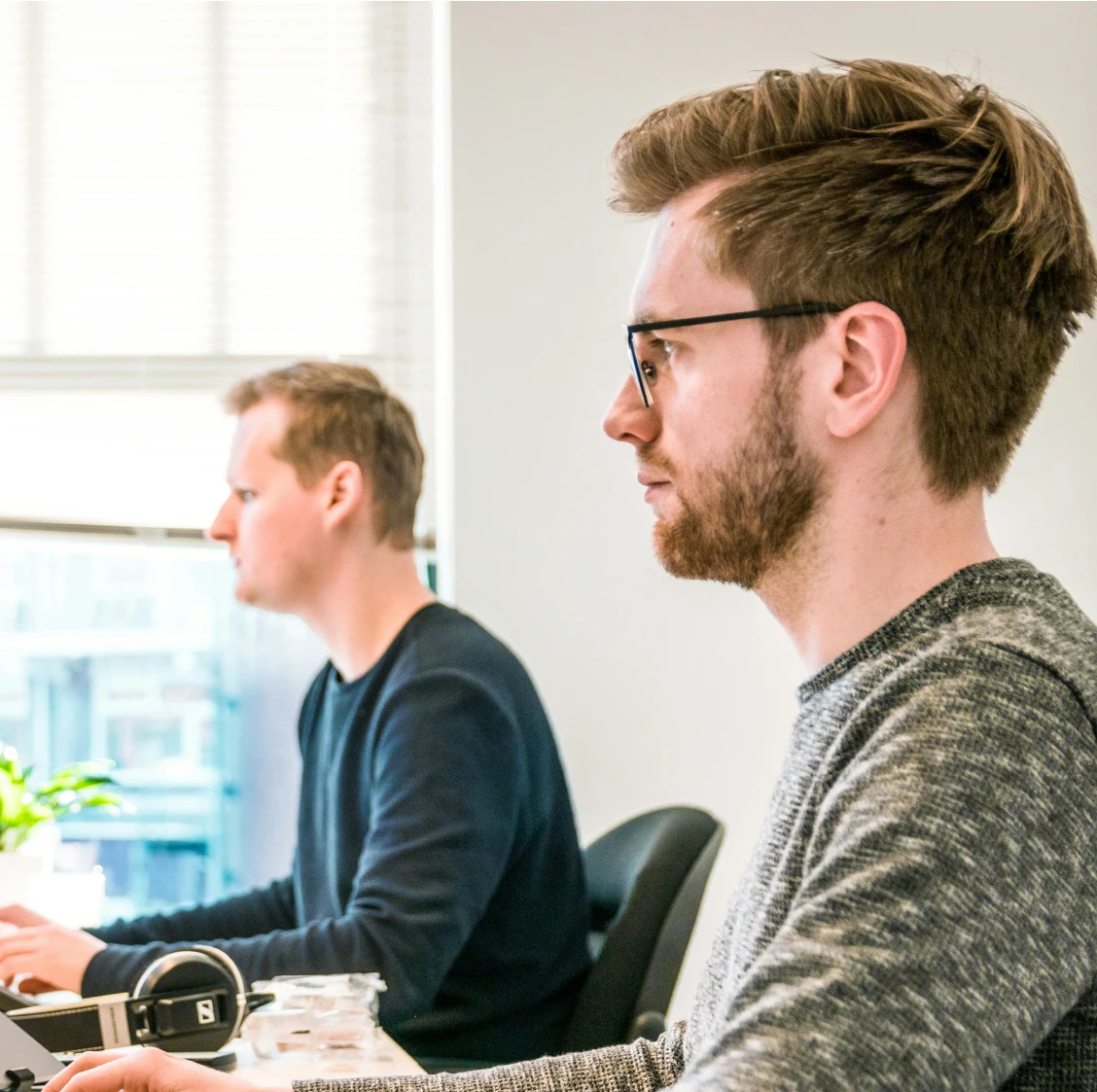 a couple of men sitting at a table with laptops