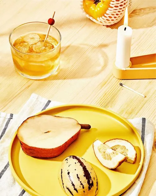 VSCO Preset AU1 on table setting of fruit on a yellow plate with a cocktail and candle by food photographer Cody Guilfoyle