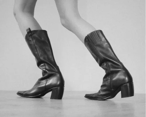 Black and white grainy photo using VSCO Preset IH5 of legs and black leather boots taken by professional photographer lessaiv