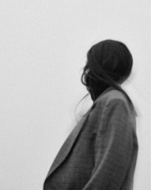 Grainy black and white photo of a woman in a blazer looking away by portrait photographer lessaiv