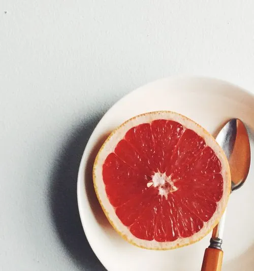 Cropped photo of a half grapefruit on a plate with a spoon taken by a professional food photographer Mark Weinberg