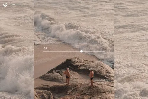 Two swimmers standing on rock surrounded by crashing ocean waves edited for image tone to adjust highlights and shadows