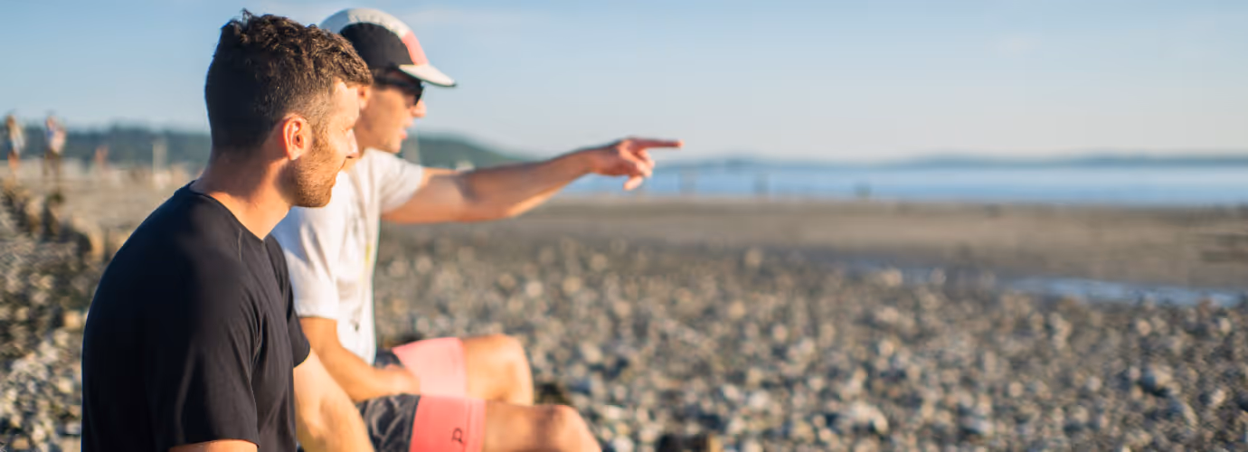 Two men sitting on a beach wearing Pacterra Athletics shorts submitted by a freelance photographer