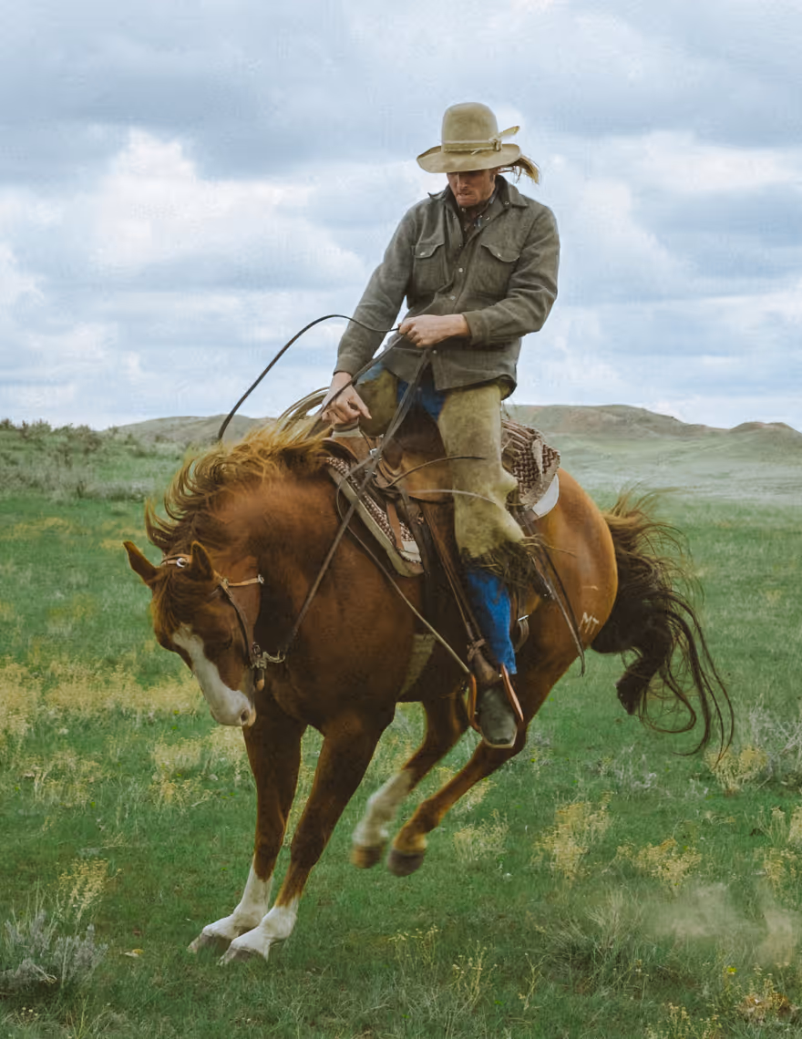 Cropped image of a man riding a bucking horse