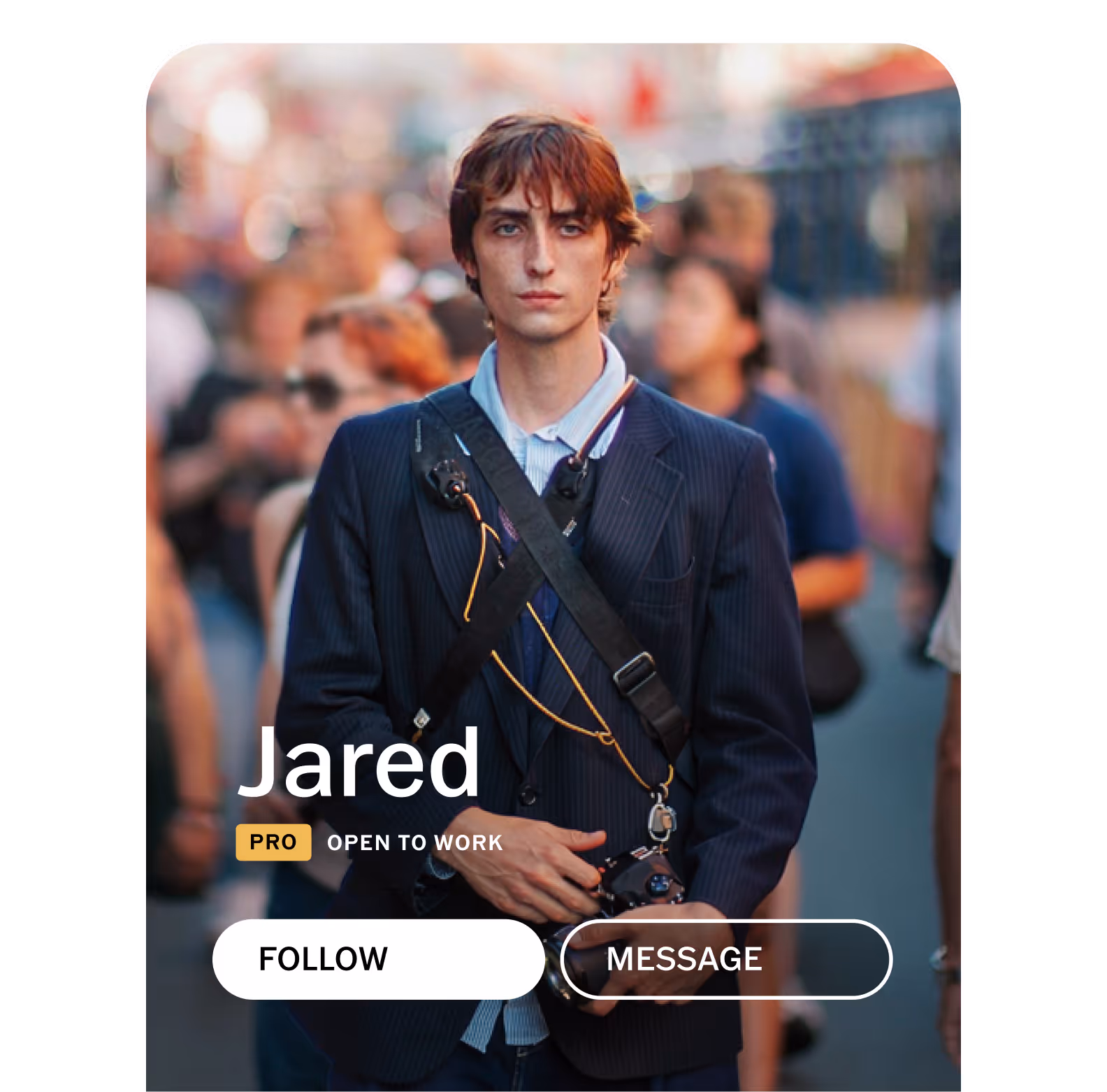 VSCO community profile for photographer Jared wearing a navy blazer holding a camera with a strap across his chest, standing on a busy street with profile UI labels PRO, Open for Work, Follow, and Message