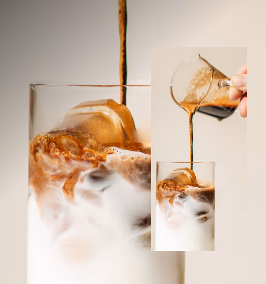 Close-up of iced coffee with milk in a glass as coffee is poured over ice cubes.
