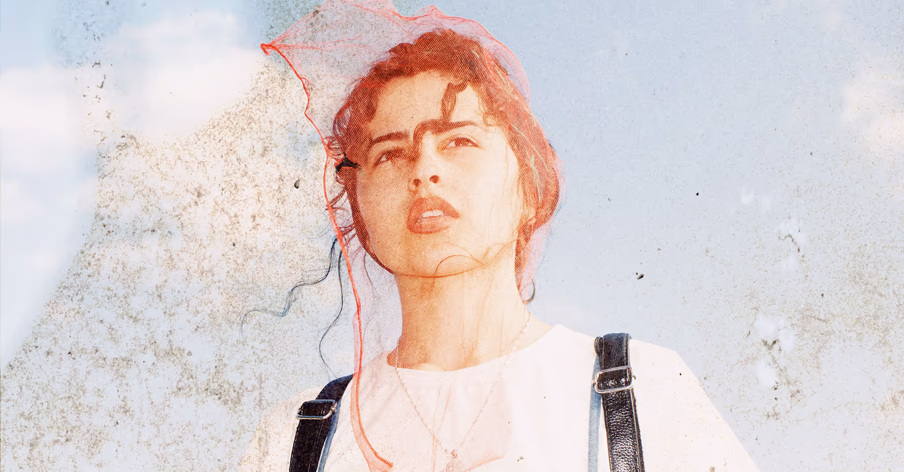 Young woman wearing a red mesh veil on her head looking upwards against a blue sky background with a textured, vintage effect.