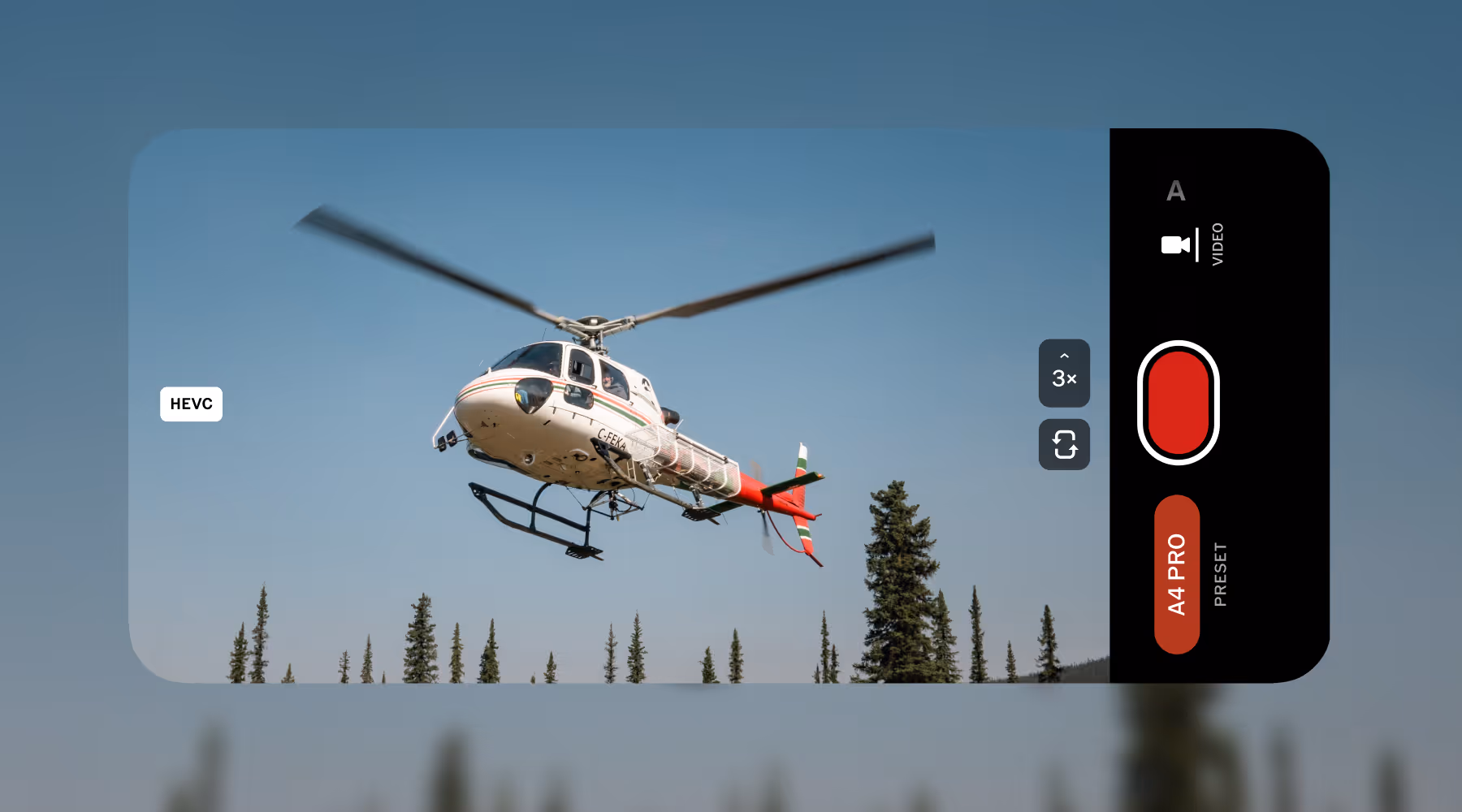 White and red helicopter flying above pine trees captured on a phone screen VSCO Capture camera app interface in video mode.