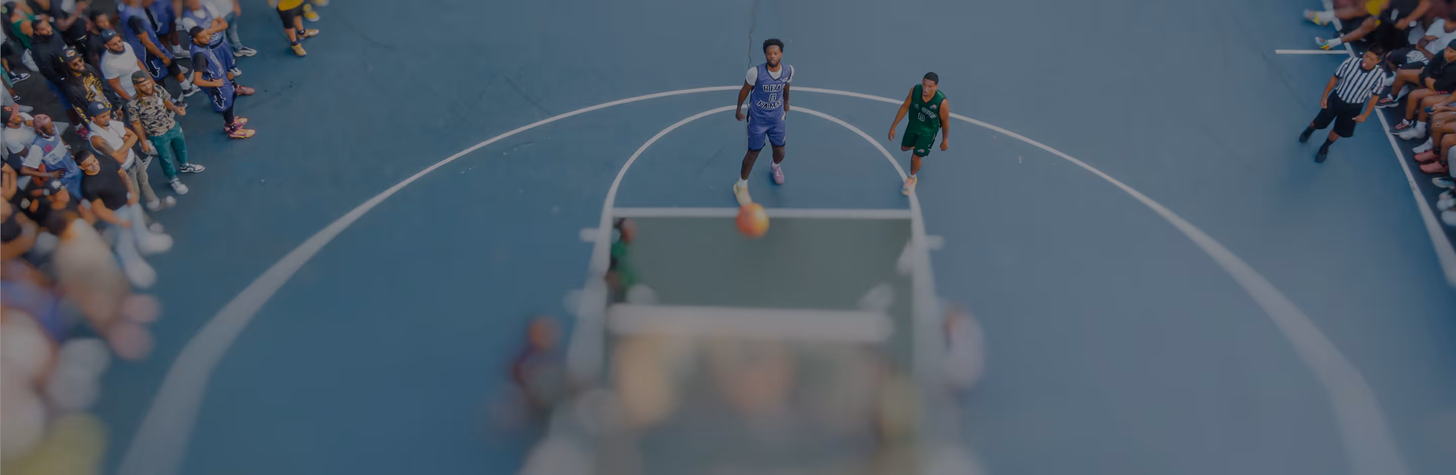 Tilt shift effect on image of a basketball game viewed from above focusing on two players near the free-throw line with a crowd watching from the sidelines.