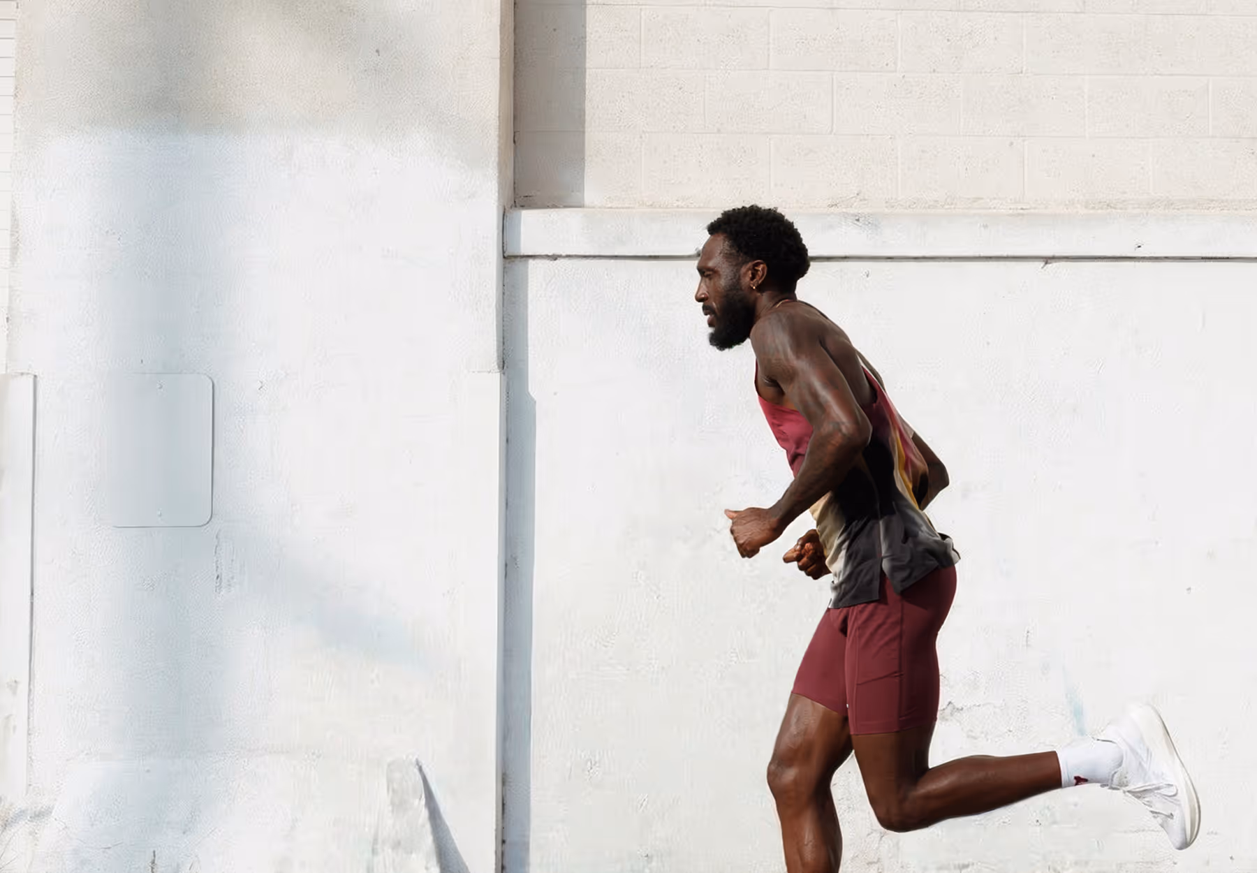 Professional photoshoot of a man running outdoors against a white wall that was cleaned up with AI background removal tool.