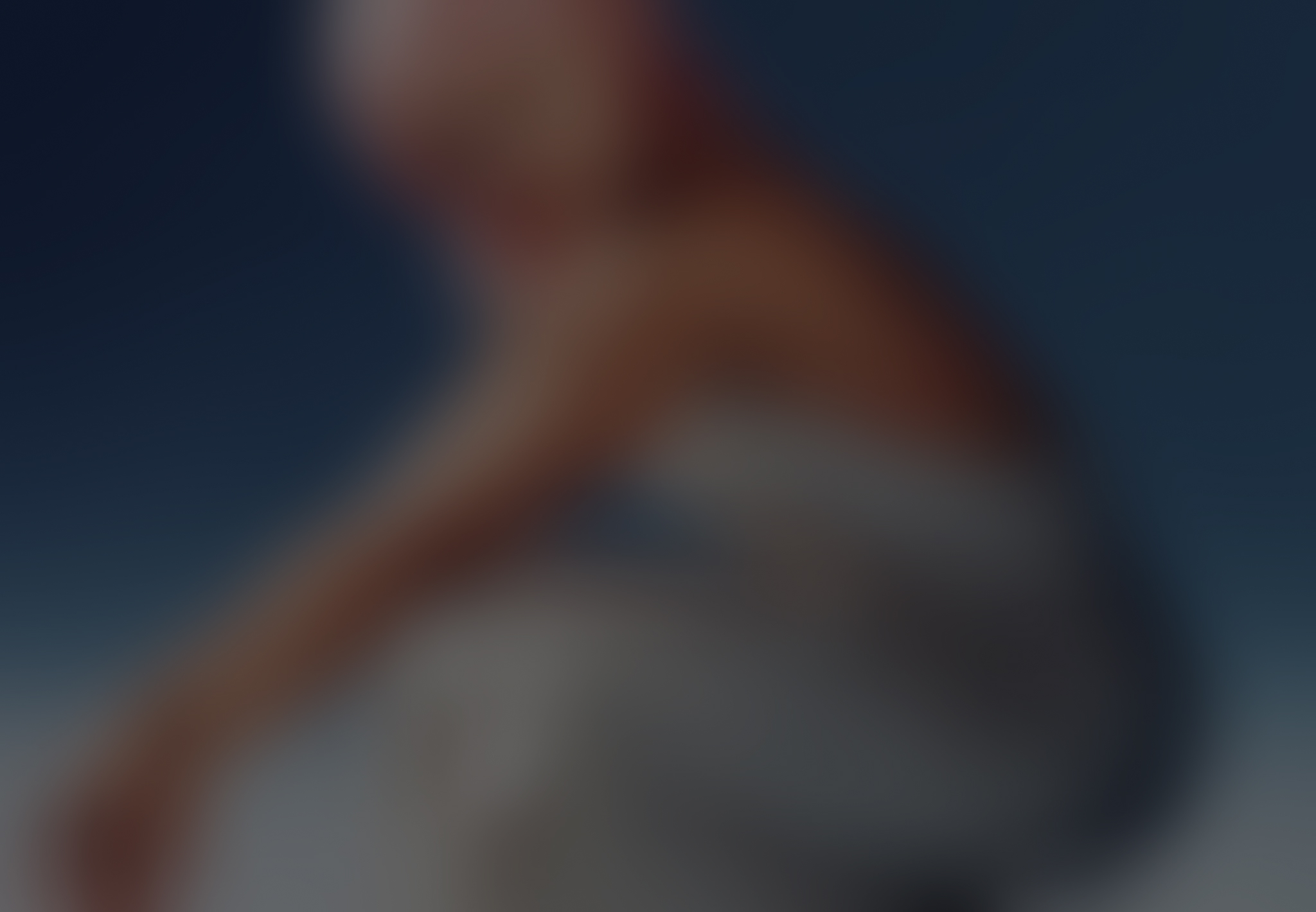 Blurry image of a person sitting with arms resting on knees against a gradient blue background.