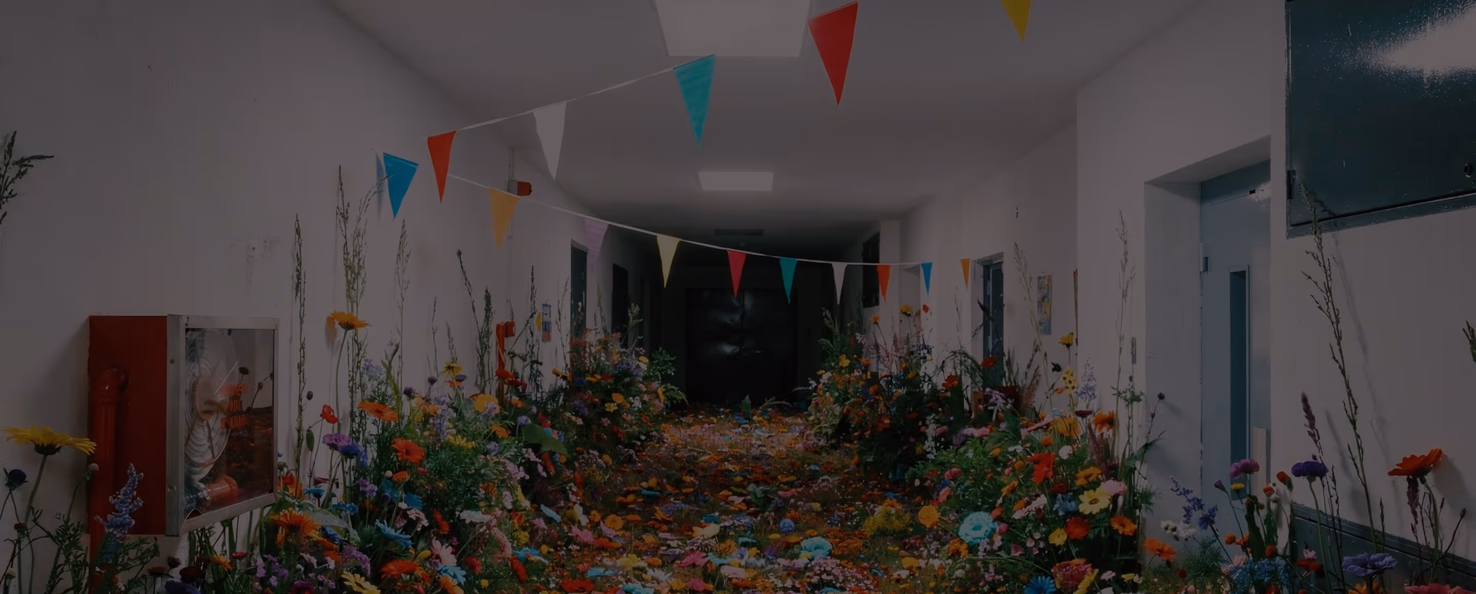 Hallway decorated with colorful flowers along the floor and walls, and a string of multicolored pennant flags hanging from the ceiling.