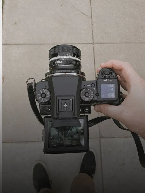 Top view of photographer Brian White holding a digital camera with lens, showing camera settings and street scene on the screen.