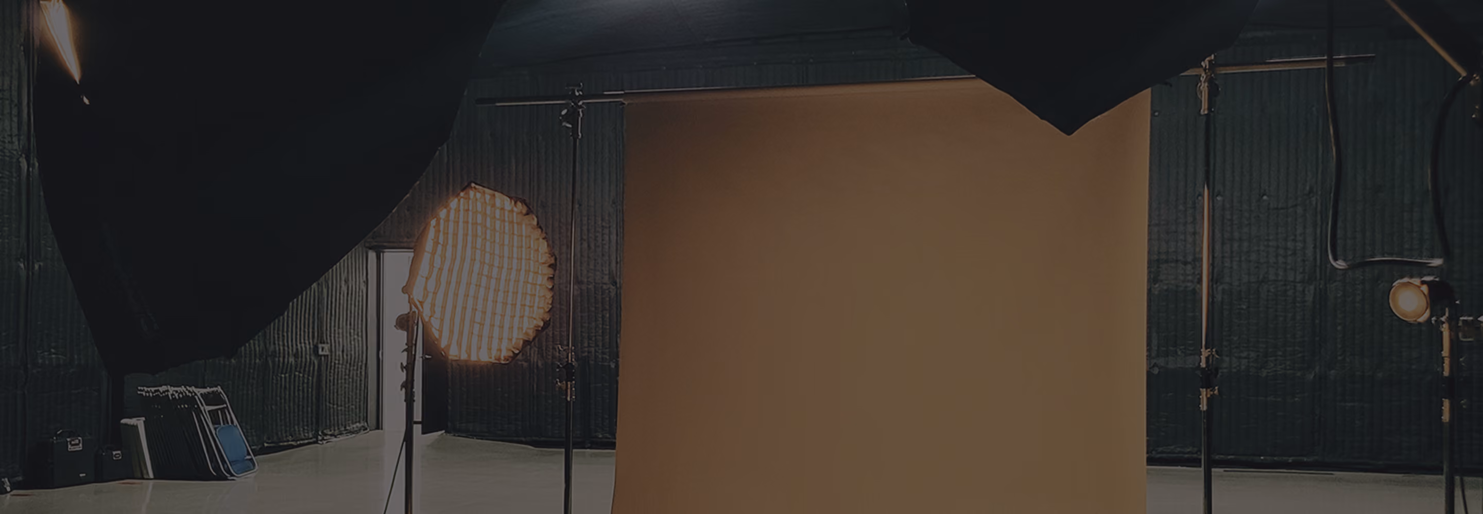 Empty photo studio with brown backdrop and studio lights on stands.