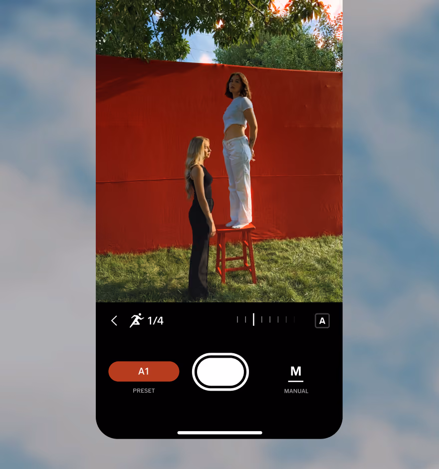 RAW camera app screen showing two women, one standing on a red stool, against a red backdrop outdoors.